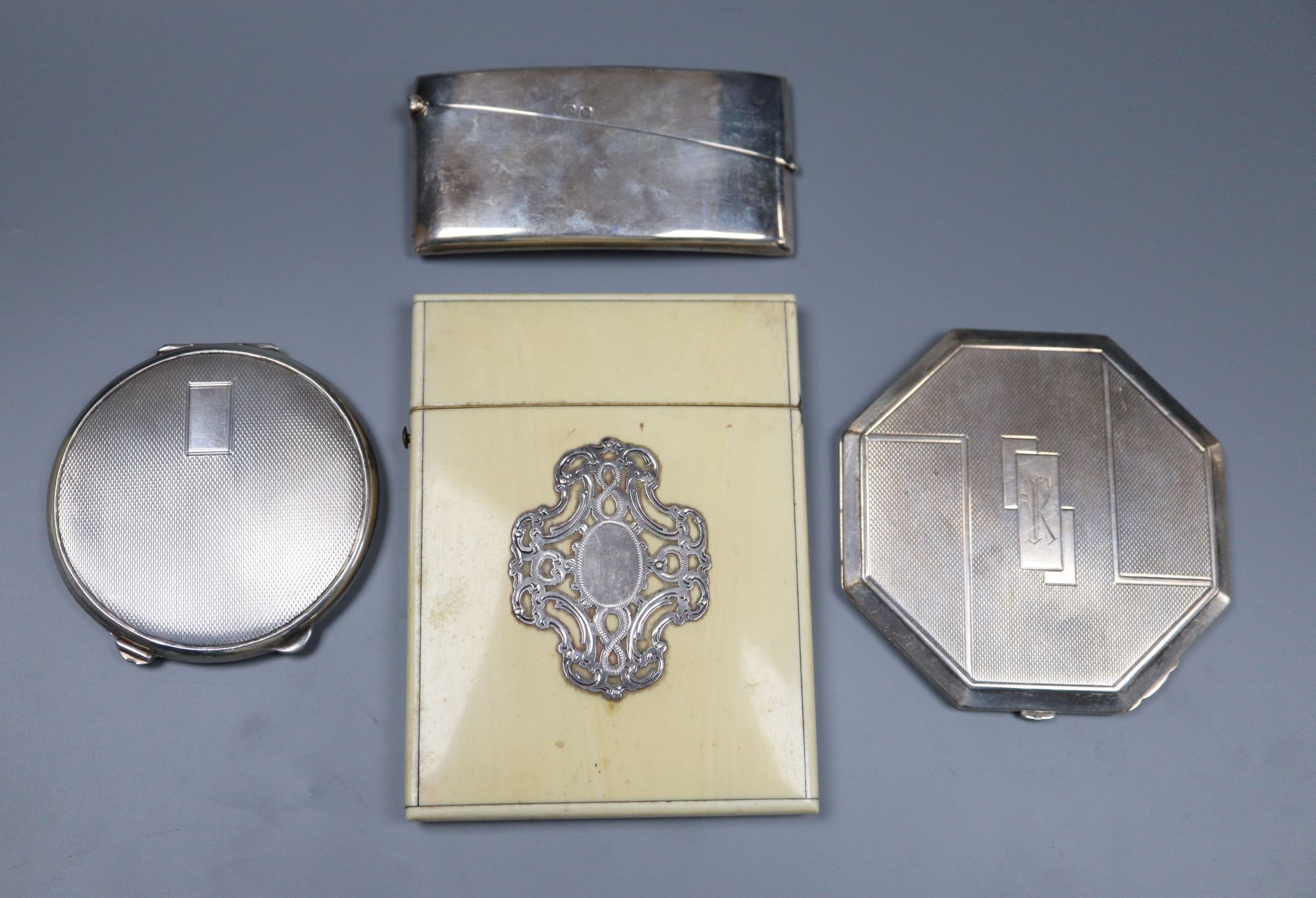 A George V silver concave card case, 82mm, two silver compacts and an ivory card case